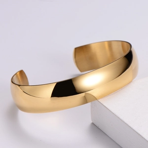 Close-up of golden Mobius cuff bracelet featuring a mirror-polished finish on white stone