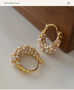 Macro shot of gold-plated hoop earrings featuring micro-set pearls and shimmering zircons