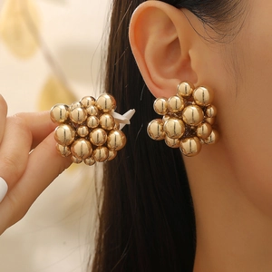 Macro shot of gold clustered bead earrings with a polished metallic finish on model