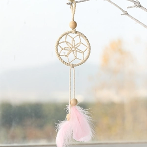 Pink feather dream catcher Christmas ornament with wooden beads hanging on a tree branch