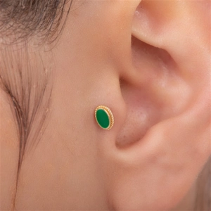 Macro close-up of a gold s925 silver ear stud with a green oval opal on the cartilage