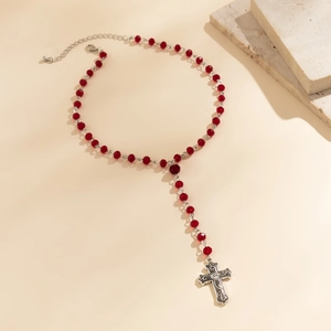 Macro shot of red faceted beads and silver hollow cross pendant with lobster clasp