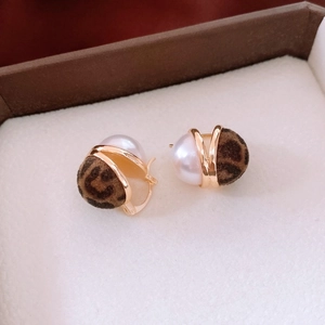 Close-up of pearl and leopard print flocked spherical earrings with gold metal accents