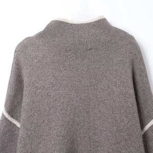 Detail of grey-brown knit sweater showing white contrast trim and neck stitching