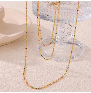 Detail of gold titanium chain necklace featuring colorful beads on a glass vessel