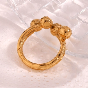 Detail of 18K gold-plated textured anxiety ring with spheres on a water-beaded surface