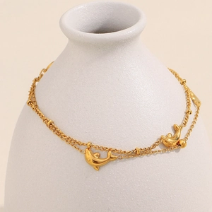 Close-up of golden dolphin charms on a layered stainless steel chain for women