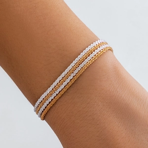 Set of four minimalist gold and silver woven chain bracelets shown on a wrist