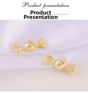 Detailed view of two gold-plated candy-shaped pendants with rhinestones on white satin