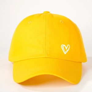 Detailed close-up of yellow cotton baseball cap with embroidered white heart pattern