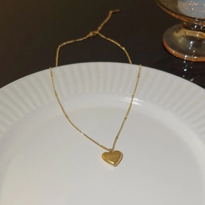 Close-up of a polished gold heart pendant with Love engraving on a ceramic plate