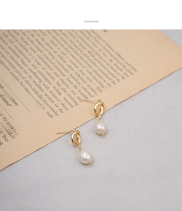 Detail of French vintage knot earrings with white freshwater pearls on textured fabric
