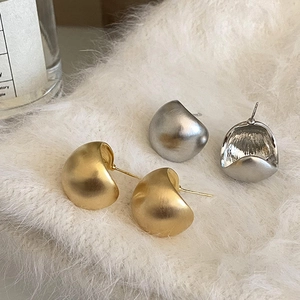 Dettaglio di orecchini a lobo opachi oro e argento su pelliccia sintetica bianca