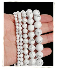 Detailed comparison of five sizes of natural white howlite beads held in hand