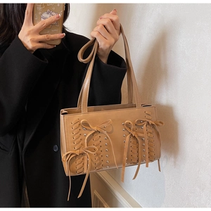 Detail of khaki PU shoulder bag with woven rope design, bow tassels and silver rivets