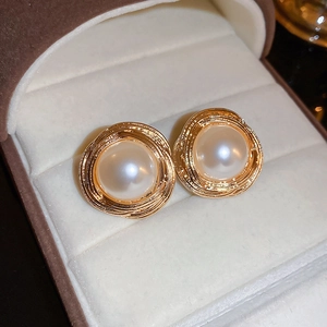 Close-up of vintage golden spiral metal earrings with center faux pearls in a jewelry box