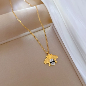 Vue macro du pendentif abeille dorée avec strass clairs et noirs sur sa chaîne