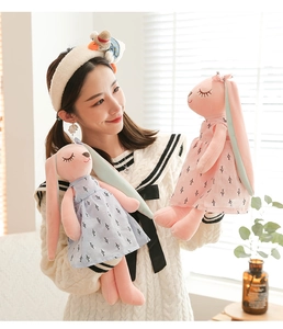 Detail of plush bunny dolls in floral dresses being held by a model in soft light
