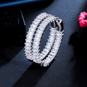 Macro shot of silver C-shaped earrings with three rows of sparkling baguette cubic zirconia