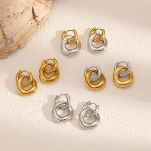 Boucles d'oreilles doubles anneaux entrelacés or et argent sur surface minimaliste