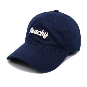 Detailed close-up of white Peachy cursive embroidery on a dark blue cotton baseball cap