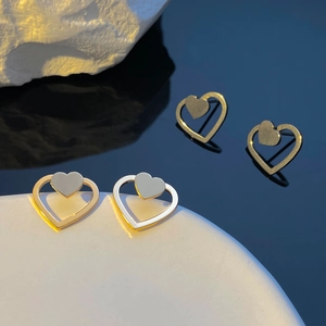 Orecchini a perno a cuore intrecciati oro e argento su un supporto espositivo minimalista