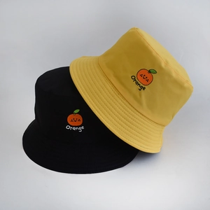 Detail of embroidered orange fruit and text on black and yellow reversible bucket hats