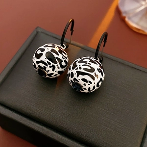 Macro shot of silver needle leopard print ball earrings on a textured gift box