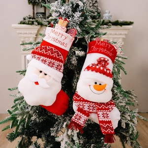 Knitted Christmas stockings with Santa and Snowman hanging on a tree by the fireplace