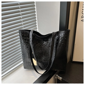Detailed close-up of glossy black crocodile embossed texture on a large tote bag