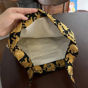 Détail de la doublure interne et du motif éléphant doré sur un sac en tissu noir