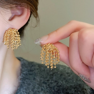 Macro detail of elegant golden fringe earrings with delicate metallic bead tassels