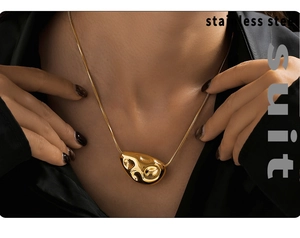 Close-up of irregular molten gold lava pendant on a sleek snake chain necklace