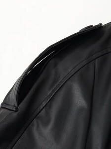 Vue détaillée de l'épaulette en similicuir noir avec des coutures soignées sur la veste