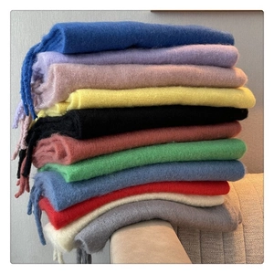Stack of colorful mohair scarves with fringes showing various vibrant knitting textures