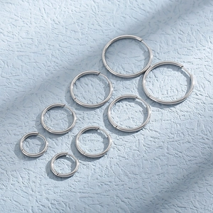 Polished silver stainless steel hoop earrings in various sizes on a blue textured background