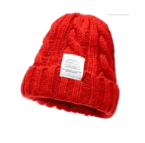 Close-up of thick red chunky knit beanie texture and white decorative brand label