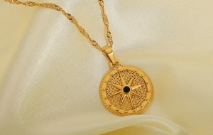 Close-up of gold water wave chain and octagram pendant with black gem on satin