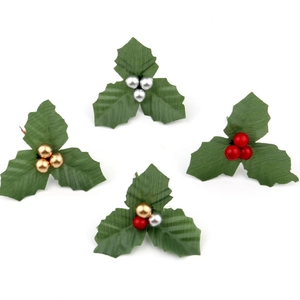 Close-up of festive DIY holly leaves with shiny berries in gold, silver, and red colors