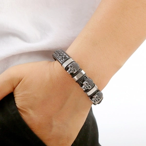 Men's woven black leather bracelet with silver skull charms and magnetic clasp