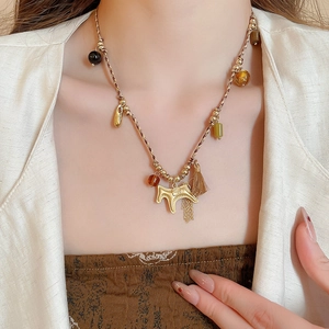 Close-up of woven rope necklace featuring a golden pony pendant and elegant tassel detail