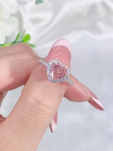Close-up of a pink heart-shaped gemstone ring with silver band worn by a model