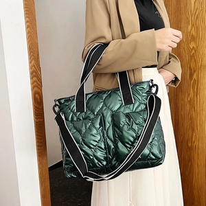 Close-up of emerald green quilted puffer bag with striped strap and glossy finish