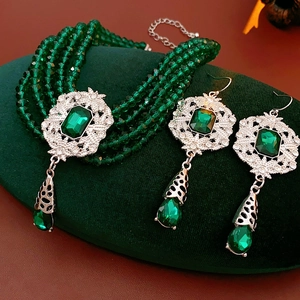 Detailed view of vintage jewelry set with emerald green stones and beaded necklace layers