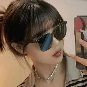 Close-up of woman wearing foldable oversized grey sunglasses and heart pendant necklace
