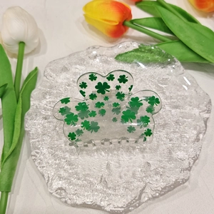 Detail shot of a transparent acrylic claw clip with green clover patterns on a glass plate