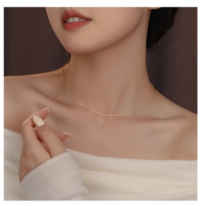 Close-up of elegant 18K gold water wave chain necklace on woman's collarbone