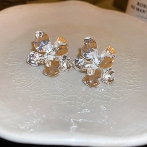 Detail view of silver petal earrings with textured metal finish on a ceramic plate