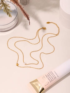 Close-up of a double-layered 18K gold star and pearl necklace on a neutral background
