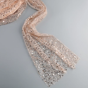 Close-up of champagne gold sequins on sheer mesh fabric of a romantic French dress